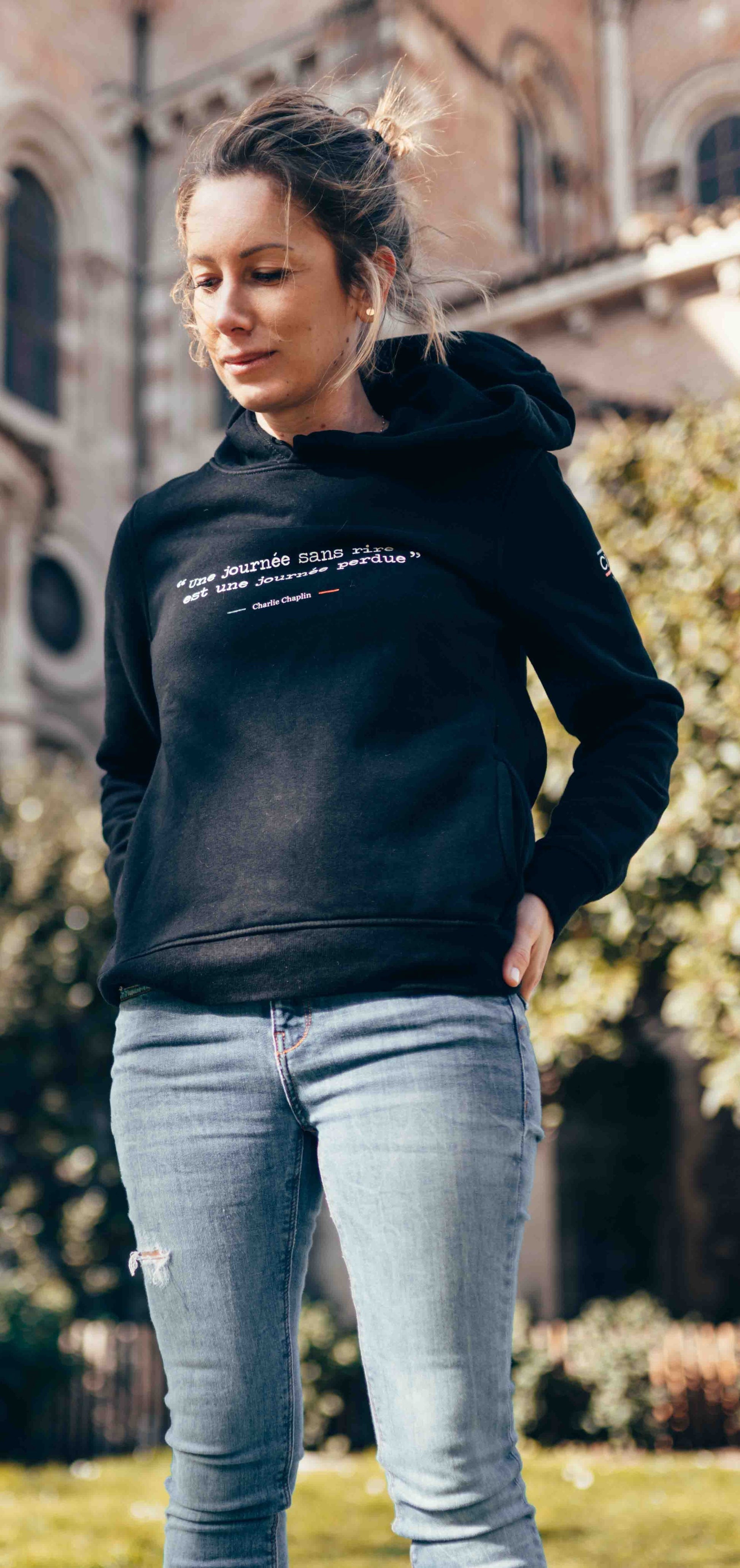 sweat femme noir en coton bio de la marque cite moi avec écrit dessus la citation de Charlie Chaplin : Une journée sans rire est une journée perdue